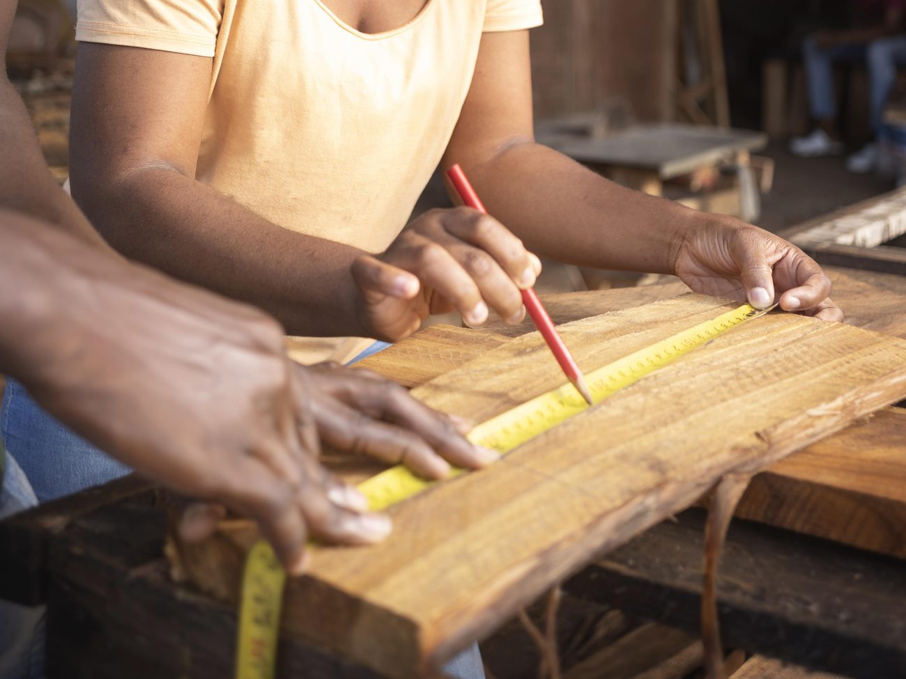 Craftsmen measuring and planing hardwood in the Beaverwoods workshop